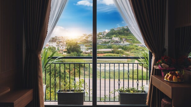 A balcony with a view of a green hillside and buildings. - Green Eco Hotel Dalat (Xuan Huong - Da Lat)