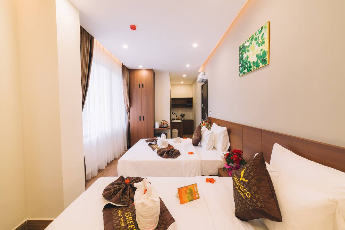 A hotel room with two beds, a bathroom, and a kitchenette.