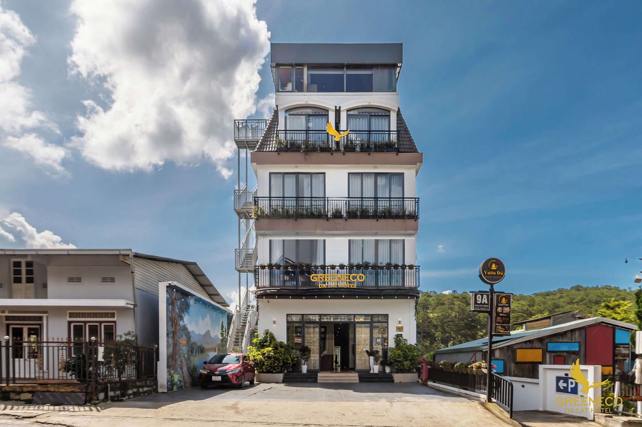 A multi-story hotel with a balcony on the second floor, a sign indicating a restaurant, and a parking sign with the number 9A.