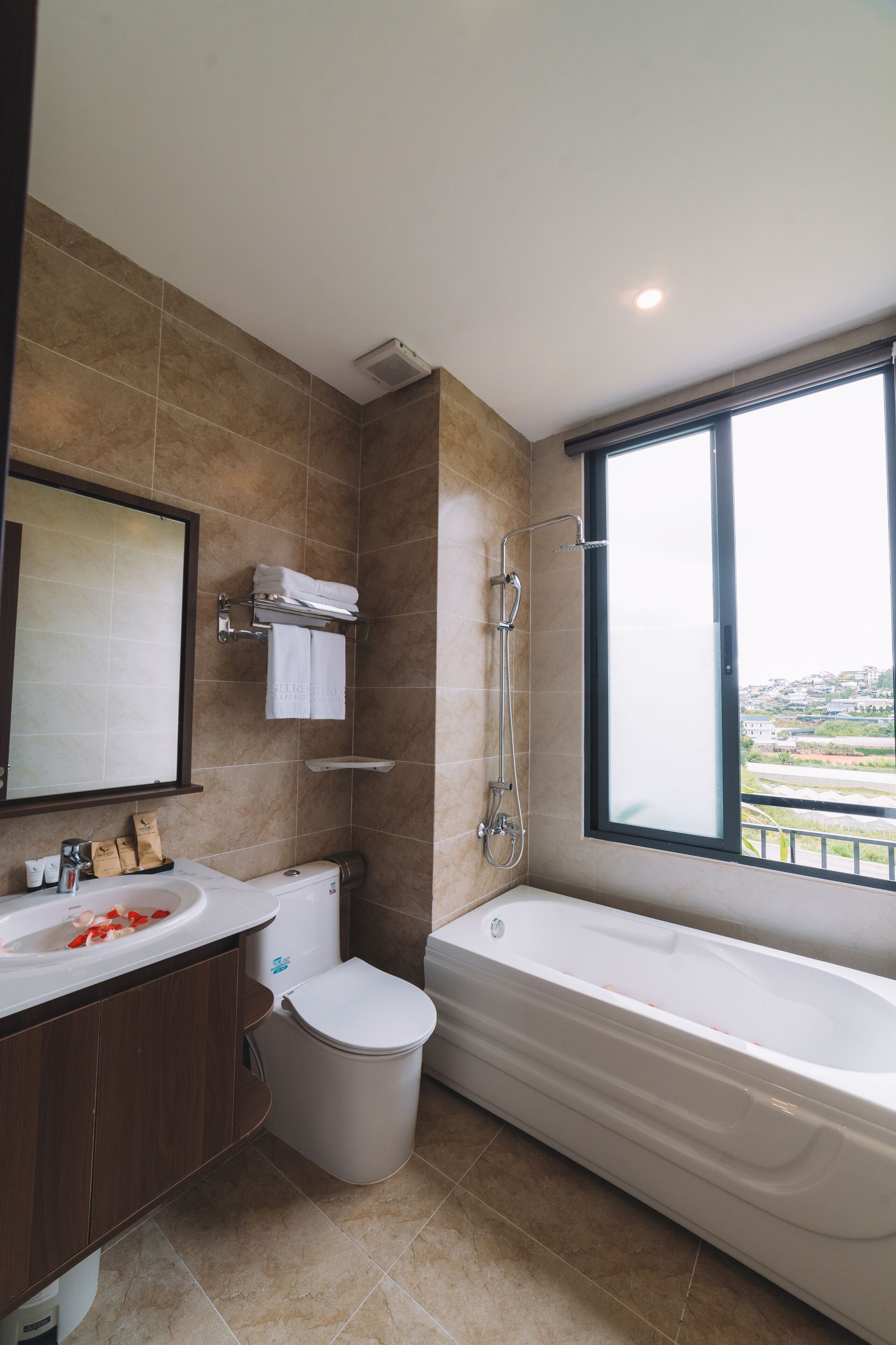 Un baño moderno con bañera, inodoro, lavamanos y un amplio ventanal con vistas.