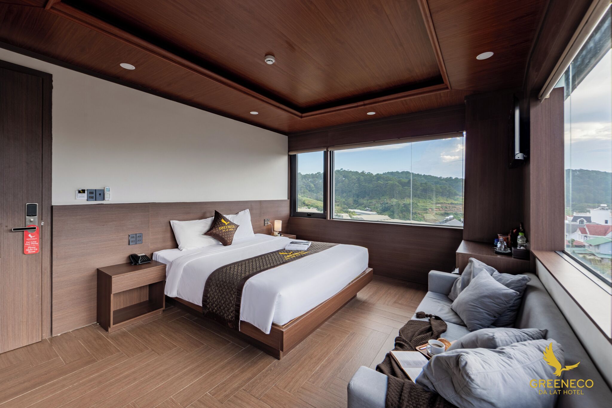 A modern hotel room with a large bed, a sofa, and a view of the countryside.