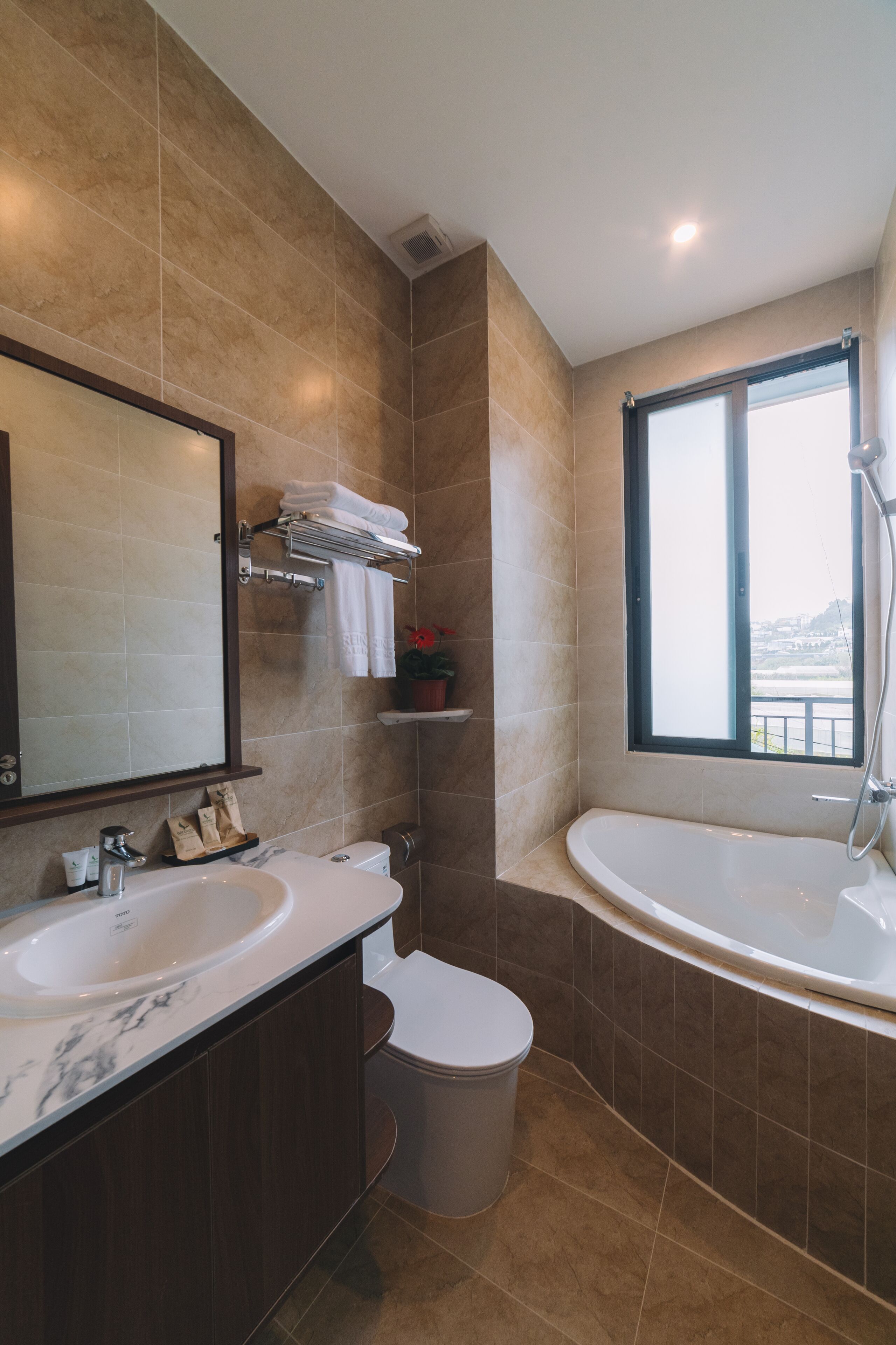 A modern bathroom with a large mirror, two sinks, a toilet, and a bathtub.