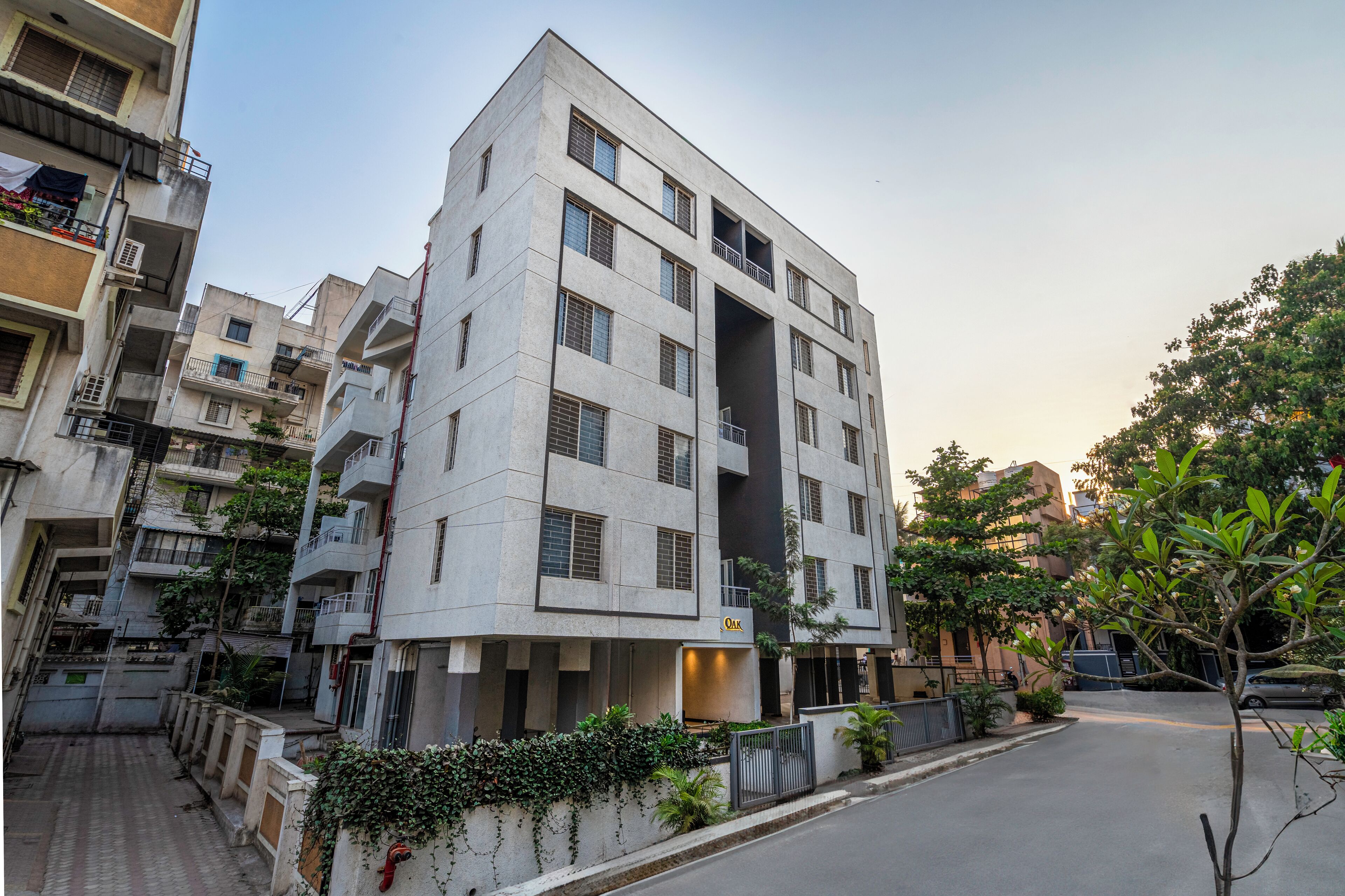 A multi-story residential building with balconies, a gated entrance, and a paved driveway.