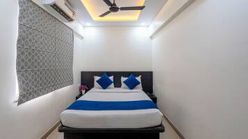A modern bedroom with a bed, a ceiling fan, and an air conditioning unit.