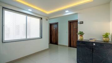Un hall d’hôtel doté d’une grande fenêtre, d’un comptoir de réception et d’un meuble en marbre foncé.