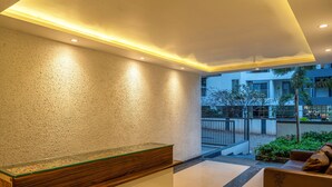 A reception area with a wooden reception desk, a glass partition, and a brown sofa.