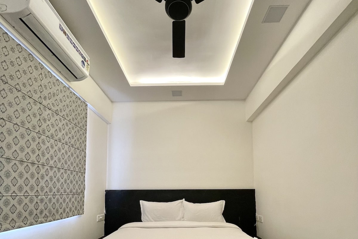 Une chambre à coucher avec un lit, un ventilateur de plafond et un appareil de climatisation.