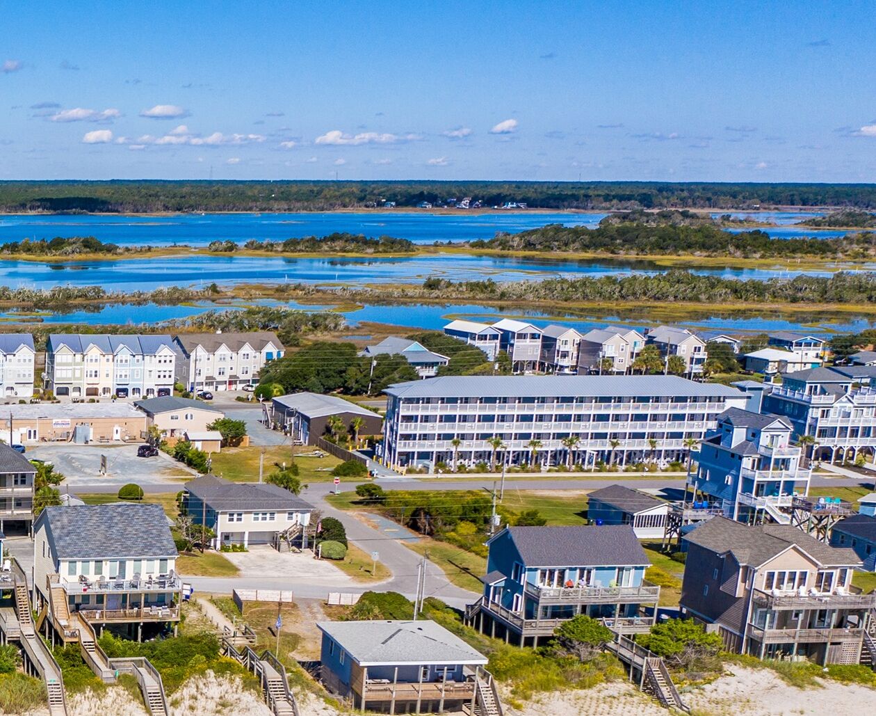 A coastal residential area with multiple buildings, including a large hotel with multiple floors and balconies, situated near a body of water.