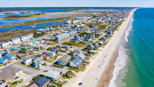 Vista aérea de una zona residencial costera con casas, una playa y un paisaje pantanoso.