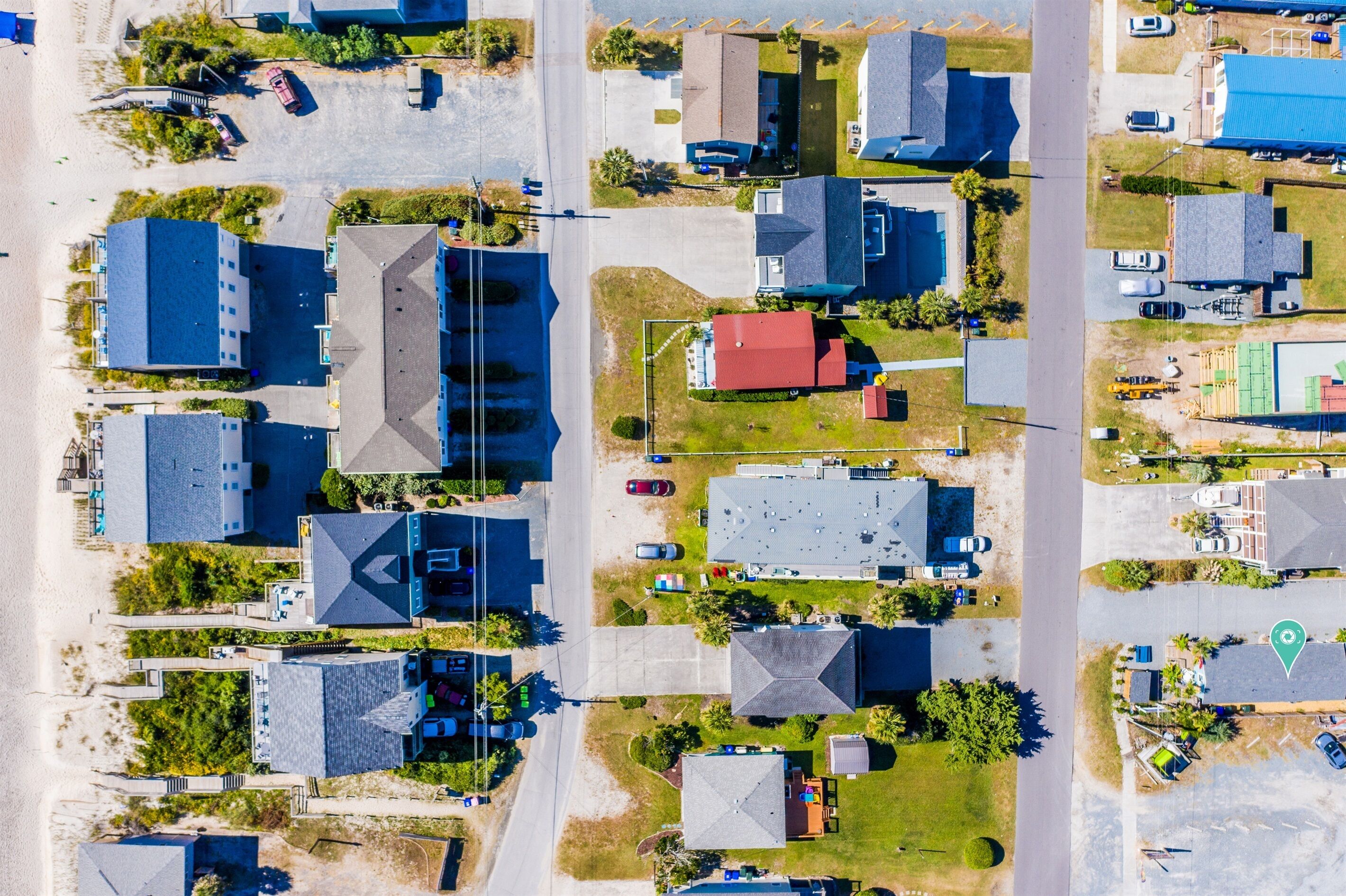 An aerial view of a residential area with multiple houses, roads, and a beach.