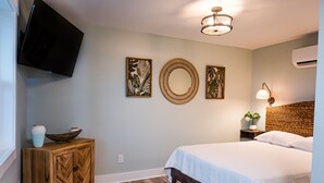 A bedroom with a bed, a wooden cabinet, a wall-mounted TV, and decorative wall art.