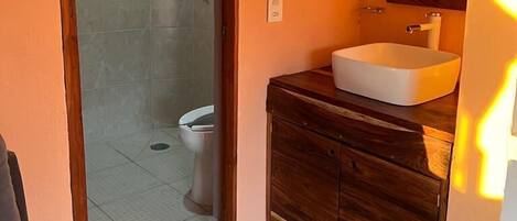 Un baño con ducha, inodoro y tocador con espejo.
