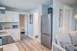 A compact kitchen with white cabinets, a microwave, and a refrigerator.
