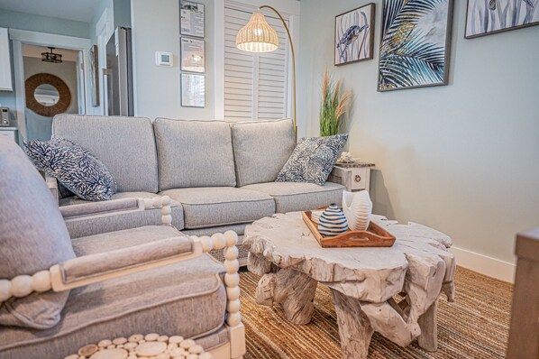 A living room with a grey sofa, a wooden coffee table, and a patterned armchair.