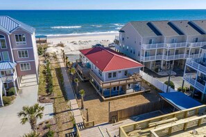 A beachfront property with a red-roofed building, a wooden deck, and a beach view.