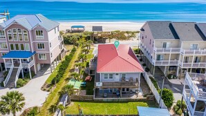 A beachfront property with multiple buildings, including a large house with a red roof and a smaller structure with a blue roof.