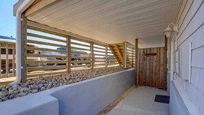 A covered outdoor area with a wooden railing, a concrete ledge, and a view of parked cars.