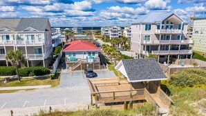 A beachfront property with multiple buildings, a red-roofed house, and a wooden deck.