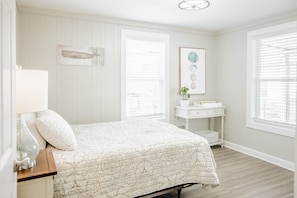 A bedroom with a bed, a nightstand, a dresser, and a window with blinds.