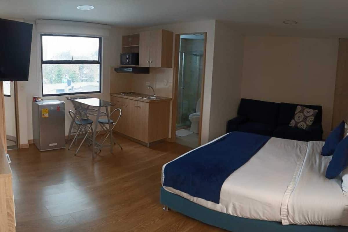 A bedroom with a bed, a desk, and a TV.