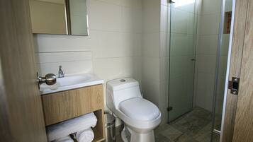 Un baño moderno con inodoro, lavabo y cabina de ducha con mampara de vidrio.