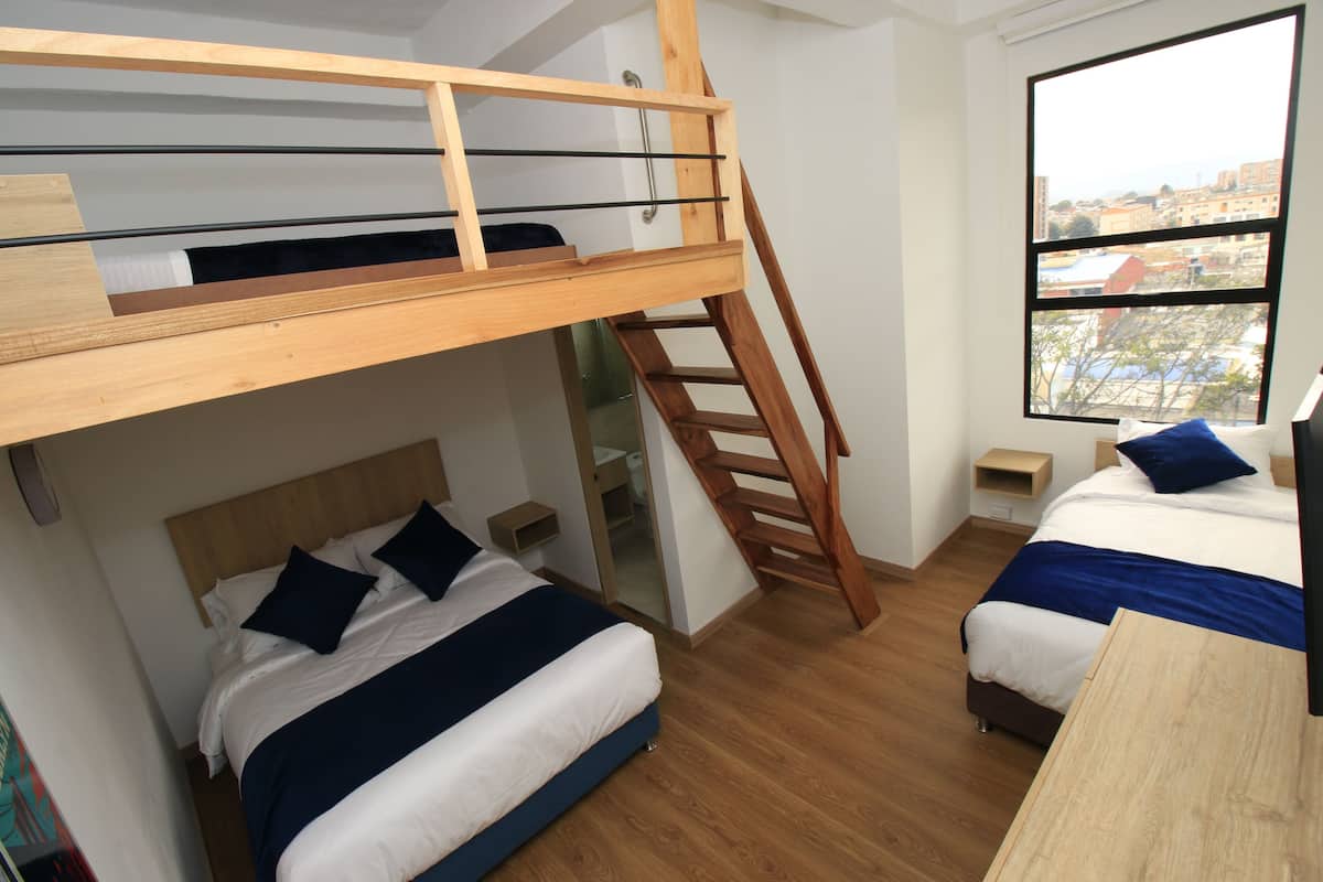A room with a bunk bed, a desk, and a window with a city view.