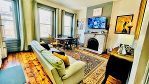 Ein Wohnzimmer mit einer Couch, einem Kamin, einem Esstisch und einem Fernseher.