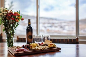 Un tavolo con un tagliere di salumi, una bottiglia di vino e un vaso di fiori.
