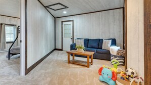 Una sala acogedora con un sofá azul, una mesa de centro de madera y una escalera que lleva a otra habitación.