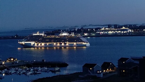 A large cruise ship docked at a port with several smaller boats nearby. - Tuukkaq Apartments (Nuuk)
