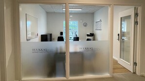 A hallway with frosted glass doors leading to a reception area. - Tuukkaq Apartments (Nuuk)