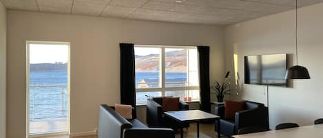 Un salon moderne avec une grande fenêtre, un canapé, une table à manger et un téléviseur.