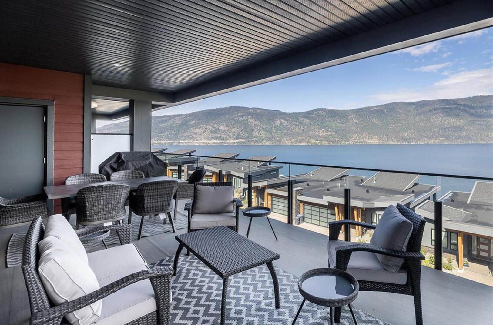 Un balcón con mobiliario exterior, vista al mar y paisaje montañoso.