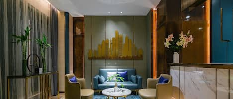 A modern interior with a blue patterned rug, a sofa, two armchairs, a round coffee table, and a cityscape wall art.
