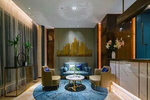 A modern interior with a blue patterned rug, a sofa, two armchairs, a round coffee table, and a cityscape wall art. - Yitel Collection (Chengdu DuFU Thatched Cottage & Sichuan Provincial People's Hospital Station） (Chengdu)