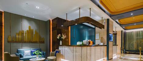 A modern hotel lobby with a reception desk, seating area, and a cityscape wall.