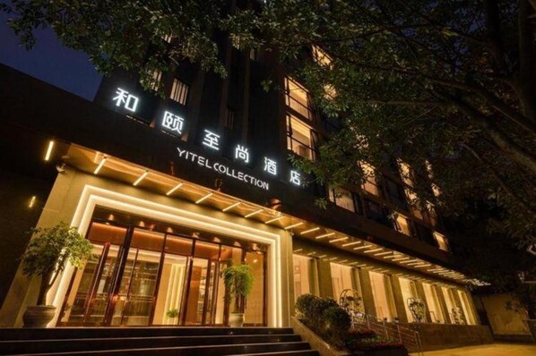 Fachada moderna de un hotel con letreros iluminados.