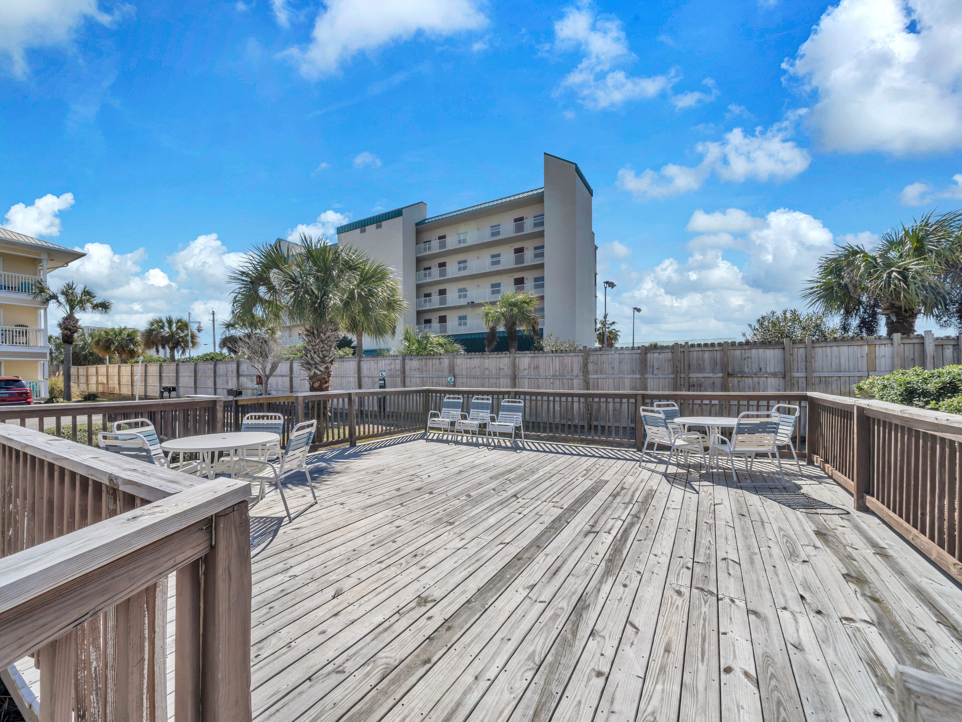 A wooden deck with outdoor seating and a view of a multi-story building in the background.