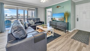 A modern living room with a leather sofa, a coffee table, and a flat-screen TV. - Beach Bella-Sleeps 8, 3 min Walk to Beach (Destin)