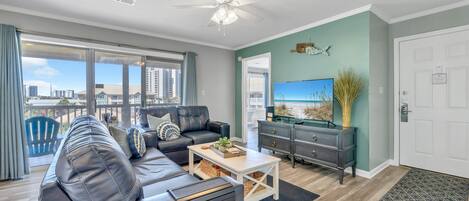 A modern living room with a leather sofa, a coffee table, and a flat-screen TV.