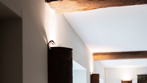 A hotel room with a bed, a nightstand, a lamp, and a wall-mounted light fixture. - The New Inn (Cirencester)