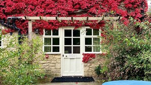 A stone house with a white door labeled "Ampney Crucis." - The New Inn (Cirencester)