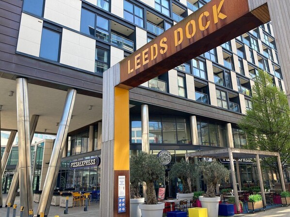Un bâtiment moderne avec une enseigne indiquant « LEEDS DOCK » et un restaurant Pizza Express.