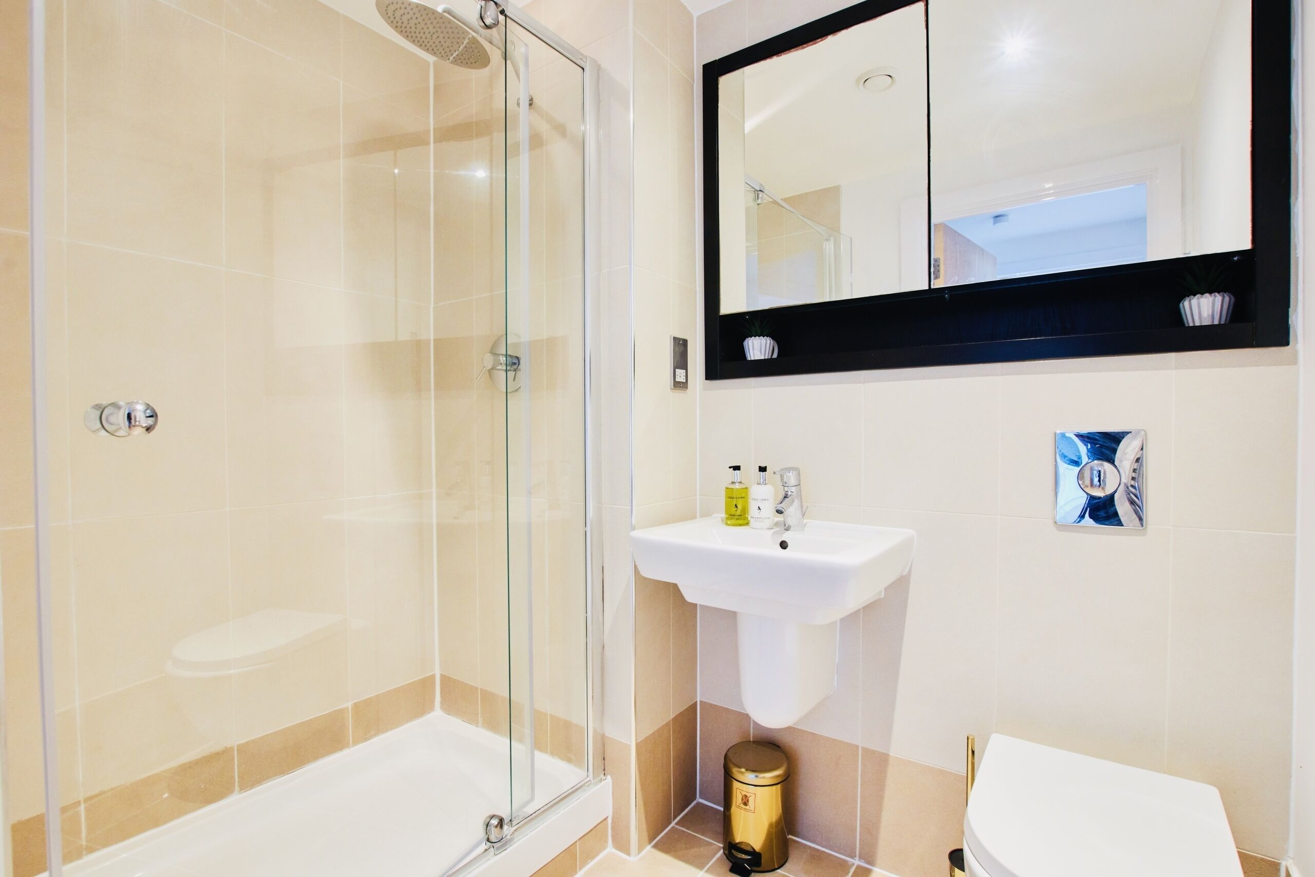 Un bagno moderno con doccia vetrata, un lavandino bianco e un grande specchio sopra il lavandino.