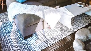 Interior acogedor de una cabaña con sofá, mesa de centro y una zona de cocina.