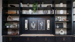 Un mobile parete in legno scuro con ripiani multipli, opere d'arte incorniciate e oggetti decorativi.