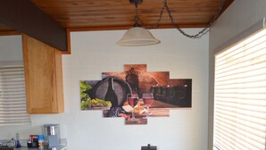 Una cocina con armarios de madera, una mesa de comedor con bancos, una lámpara colgante y una obra de arte en la pared.