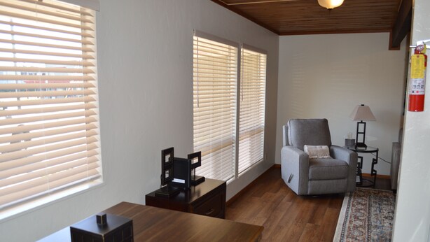 Un salón con piso de madera, un sofá gris, una mesita y un tapete estampado.