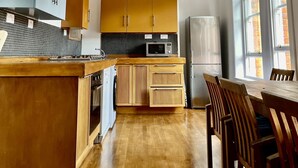 Une cuisine moderne dotée d’un îlot central, de meubles en bois, d’un four à micro-ondes et d’un coin repas avec des chaises.