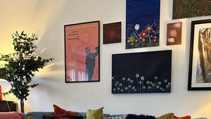 Un salon avec un canapé bleu, une table basse sur laquelle sont posés des livres et divers éléments de décoration murale.